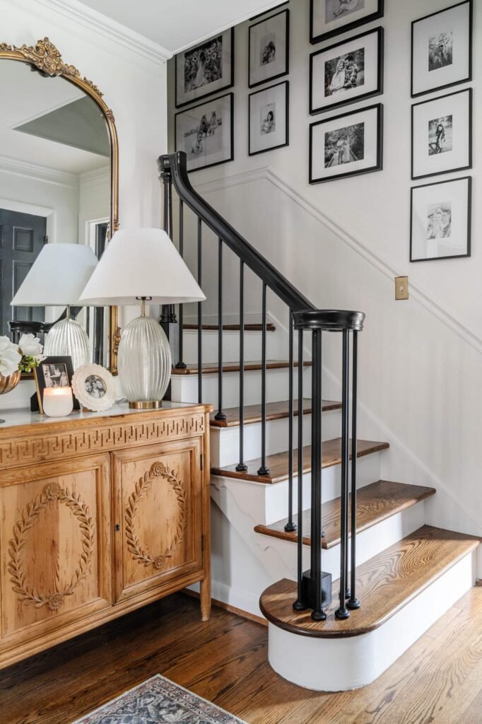 Storytelling staircase picture wall featuring photographs, artwork, and mirrors1