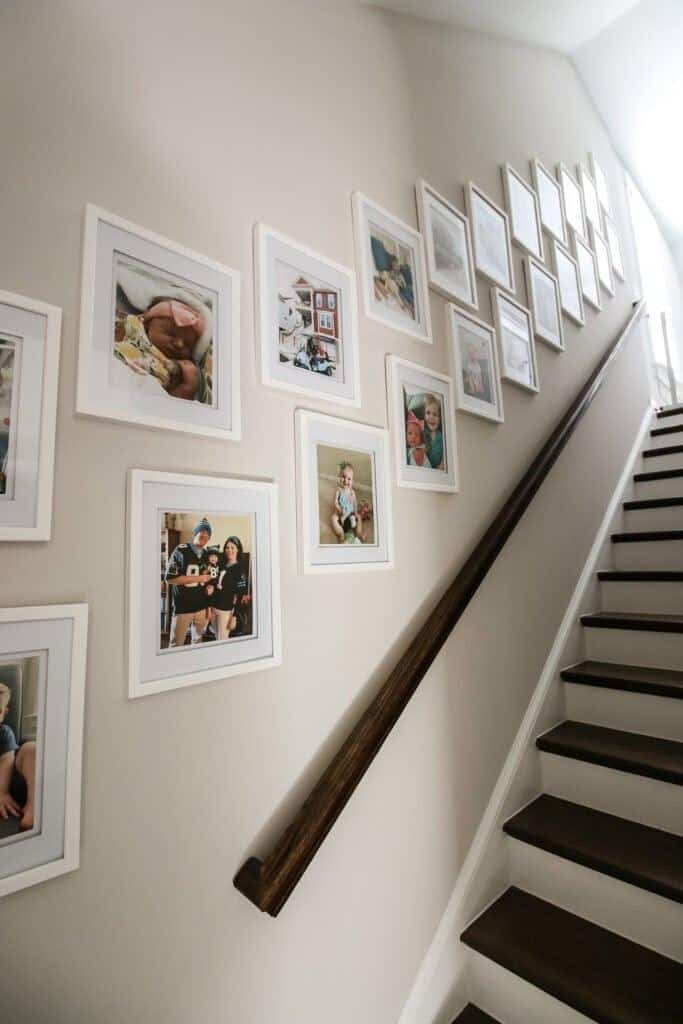 Personal family photo wall arranged elegantly beside a staircase1